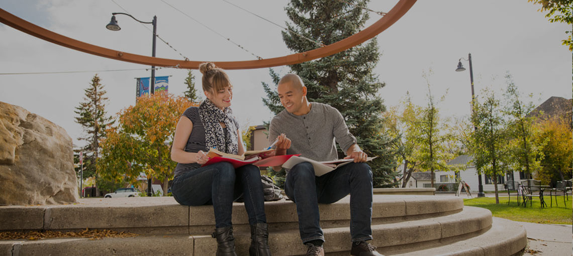 Two students reading on steps in Okotoks